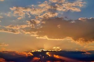 hermosa vista a los rayos de sol con algunas bengalas y nubes en un cielo azul foto