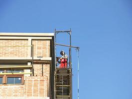 High-rise finishing works. An employee repairs the facade of a building. photo