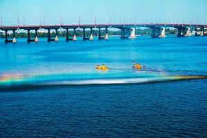 Athletes in kayaks in training near the river fountain in a rainbow of splashes. photo