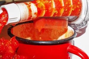 A woman prepares fresh healthy juice from tomatoes. Juicer at work. Diet concept for a healthy lifestyle. photo