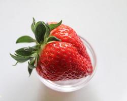 Strawberries with leaves on a plate in a glas bowl. Isolated on a white background. photo