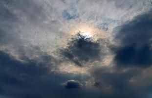 hermosa vista a los rayos de sol con algunas bengalas y nubes en un cielo azul foto