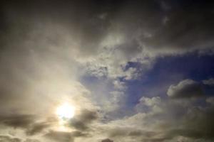 hermosa vista a los rayos de sol con algunas bengalas y nubes en un cielo azul foto