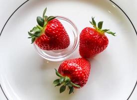 Strawberries with leaves on a plate in a glas bowl. Isolated on a white background. photo