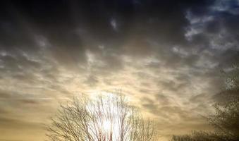 hermosa vista a los rayos de sol con algunas bengalas y nubes en un cielo azul foto