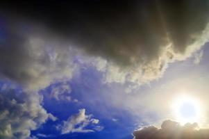 hermosa vista a los rayos de sol con algunas bengalas y nubes en un cielo azul foto