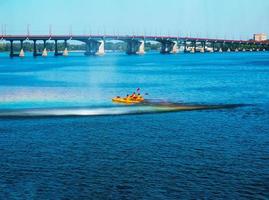 Athletes in kayaks in training near the river fountain in a rainbow of splashes. photo