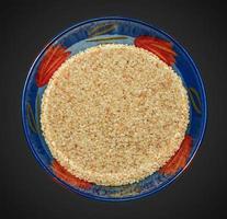 Sesame seeds in a blue glass bowl. Top view of white sesame seeds in a round bowl on a black background photo