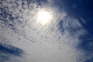 hermosa vista a los rayos de sol con algunas bengalas y nubes en un cielo azul foto