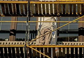 High-rise finishing works. An employee paints the facade of a building photo