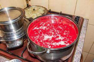 una mujer prepara jugo fresco y saludable de tomates. El jugo de tomate recién hecho se hierve en una cacerola y se conserva para almacenamiento a largo plazo. concepto de dieta para un estilo de vida saludable. foto