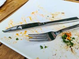 Used empty white plate with fork and knife photo