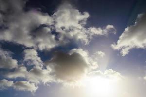 Beautiful view at sunbeams with some lens flares and clouds in a blue sky photo