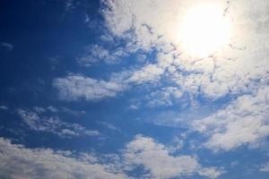 hermosa vista a los rayos de sol con algunas bengalas y nubes en un cielo azul foto