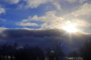 Beautiful view at sunbeams with some lens flares and clouds in a blue sky photo