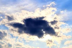 hermosa vista a los rayos de sol con algunas bengalas y nubes en un cielo azul foto