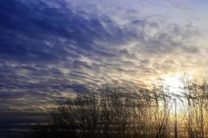 hermosa vista a los rayos de sol con algunas bengalas y nubes en un cielo azul foto