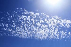 hermosa vista a los rayos de sol con algunas bengalas y nubes en un cielo azul foto