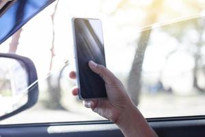 The hand of driver is using a mobile phone to help navigate or GPS while parking on the side of the road. photo