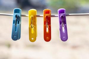 Multi colored plastic clothes clips on the wire on blur nature background. photo