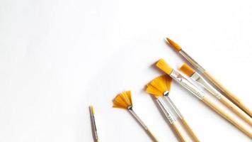 Top view of a variety of artist brushes on a white background with copy space for text. Creative postcard photo