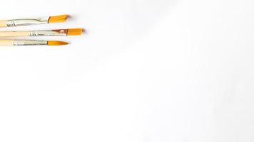 Top view of a variety of artist brushes on a white background with copy space for text. Creative postcard photo