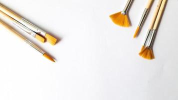 Top view of a variety of artist brushes on a white background with copy space for text. Creative postcard photo