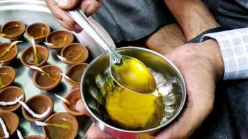 Man helping during putting oil in clay candles photo