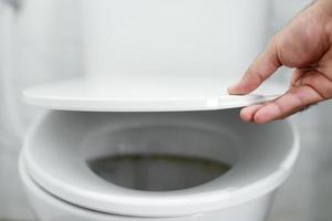 man's hand opening the toilet lid photo