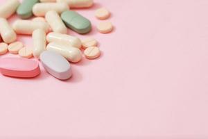 Pill bottle spilling out. colorful pills capsule on to surface tablets on pink background. drug medical healthcare pharmacy concept. pharmaceuticals antibiotics pills medicine in blister packs. photo