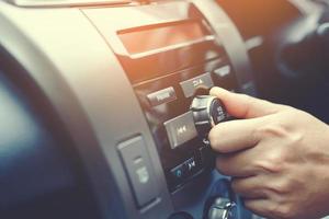 cierre la mano abierta escuchando la radio del coche. Conductor de camión cambiando las estaciones de radio de botón de giro en el sistema multimedia de su vehículo. moderno sistema de audio estéreo con pantalla táctil. concepto de transporte y vehículo foto