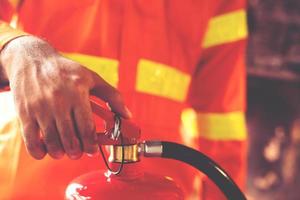 Fireman hand holding fire extinguisher. available in emergencies conflagration damage background. Safety concept. photo