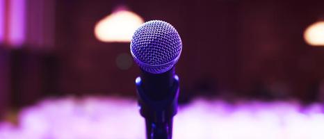 Close up of microphone on stage lighting at concert hall or conference room. copy space banner. soft focus. photo