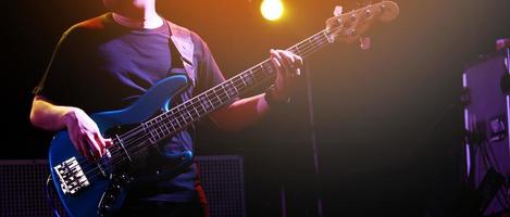 close up hand young man playing bass at recording studio rehearsal base. rock music band. photo