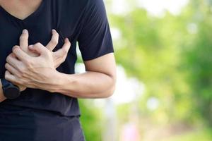 hombre con dolor de pecho - ataque al corazón al aire libre. o el ejercicio pesado hace que el cuerpo sufra enfermedades del corazón foto