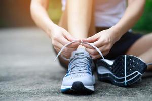 Running shoes. close up female athlete tying laces for jogging on road. Runner ties getting ready for training. Sport lifestyle. copy space banner. photo