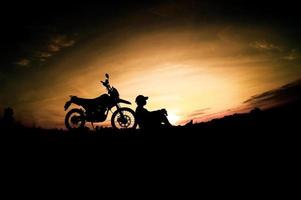 siluetas masculinas y motos de motocross. parque para relajarse en las montañas por la noche. concepto de ocio y viajes de aventura foto