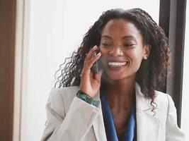 mujer de negocios negro africano persona hablar teléfono inteligente comunicación tecnología red Internet en línea vocación trabajo trabajo carrera hembra arfo cabello retrato interior oficina feliz sonrisa hermosa foto