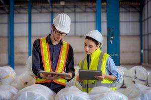 Factory engineer under inspection and checking quality production process on face mask manufacture  station by  wearing casual uniform and safety helmet in factory plantation. photo