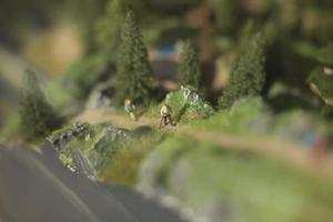 Tourists go uphill in summer. Hiking. Toy figures of people on model of mountainous area. photo