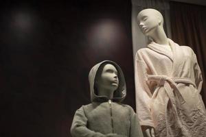 Mannequin in bathrobe. Window of clothing store. Two human figures. Child's mannequin. photo