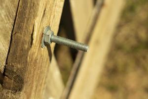 Bolt screwed into the board. Thread on the bolt. The nut is twisted on the thread. Fastening the board to the board. photo