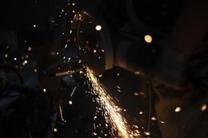 Work as grinder in workshop. Metal grinding. Sparks from high temperature. photo
