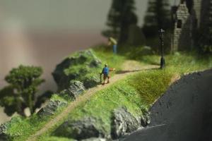 Miniature model of tourists on a mountain trail. Figures of people walking through the mountains. photo