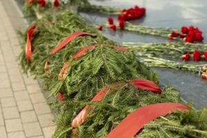 Spruce wreaths on the monument. Commemorative red ribbons on the grave of a soldier. Symbolic plants on the site of victory in the Great Patriotic War. photo