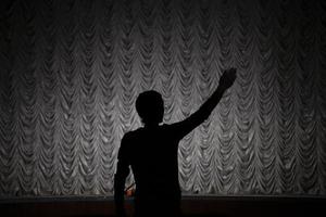 Silhouette of the director. A man directs a play. Hand gesture. photo