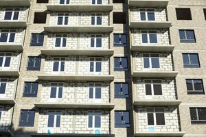 New building. Construction of an apartment building in Moscow. Residential house in sunlight. Inserted plastic windows in the house. photo