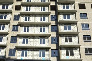 New building. Construction of an apartment building in Moscow. Residential house in sunlight. Inserted plastic windows in the house. photo