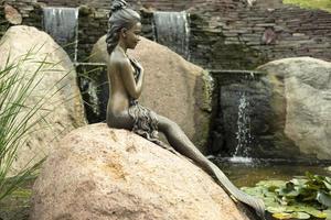 escultura de una sirena. estatua en piedra. estatua de bronce de una niña con cola. figura del parque foto