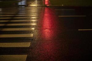 The red color of the traffic light is reflected on the pedestrian crossing. photo